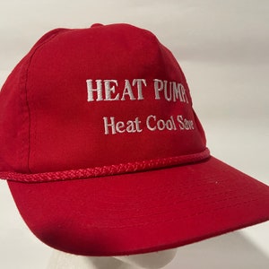 May include: Red baseball cap with white embroidered text that reads "HEAT PUMP Heat Cool Save".