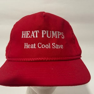 May include: A red baseball cap with white embroidered text that reads "HEAT PUMPS Heat Cool Save".