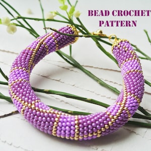 May include: A purple and gold beaded bracelet with a beaded crochet pattern. The bracelet is on a white surface with green branches.