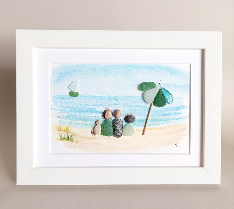 May include: A framed watercolor painting of a family of four sitting on a beach with a green beach umbrella and a sailboat in the distance.