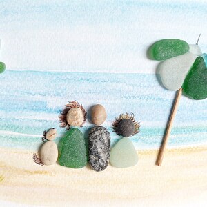 May include: A watercolor painting of a beach scene with a family of five made from sea glass and stones. The family is standing under a green and blue sea glass umbrella.