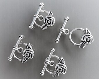 May include: Four silver-toned toggle clasps with rose accents. Each clasp features a detailed rose design with leaves.