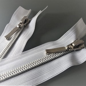 May include: Two white zipper pulls with silver metal sliders. The zippers are open and the sliders are in the middle of the zipper tape.