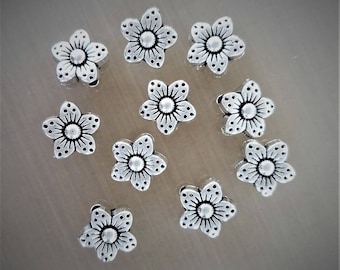 May include: Ten silver metal flower charms with a detailed design. The charms are approximately 1 inch in diameter.