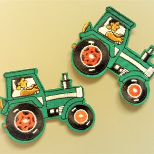 May include: Two green embroidered iron-on patches of tractors. Each patch features a cartoon driver in the cab and the words "Farm Fresh" on the side.