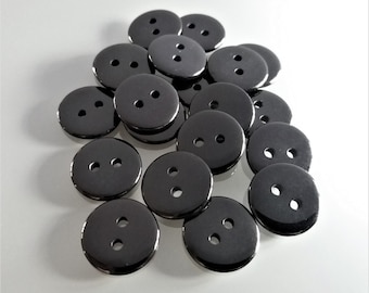 May include: A pile of black buttons with two holes each. The buttons are shiny and have a smooth surface.