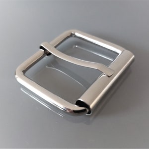 Peut inclure: Une boucle en métal argenté pour une ceinture ou une sangle. La boucle est rectangulaire avec des coins arrondis et une finition lisse et polie.