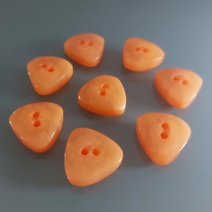 May include: Eight orange triangle-shaped buttons with two holes each.