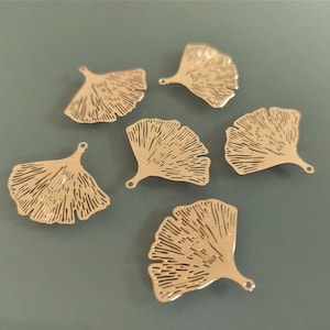 Peut inclure: Six breloques en forme de feuille de ginkgo en métal doré avec un trou en haut pour les attacher à des bijoux ou d'autres objets artisanaux.