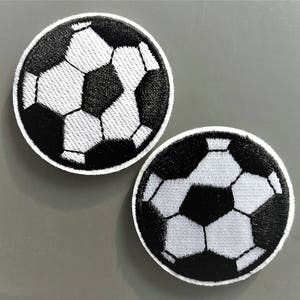 Peut inclure: Deux patchs thermocollants brodés de ballons de football noir et blanc.