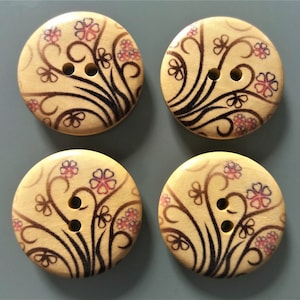 Peut inclure: Quatre boutons en bois avec un motif floral. Les boutons sont beiges avec des motifs floraux noirs et roses. Chaque bouton a deux trous.