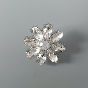 22 mm großer, silberner Knopf mit Strassblumenmuster.