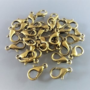 Pode incluir: Um monte de fechos de lagosta de metal dourado. Esses fechos são comumente usados para fazer joias e artesanato.