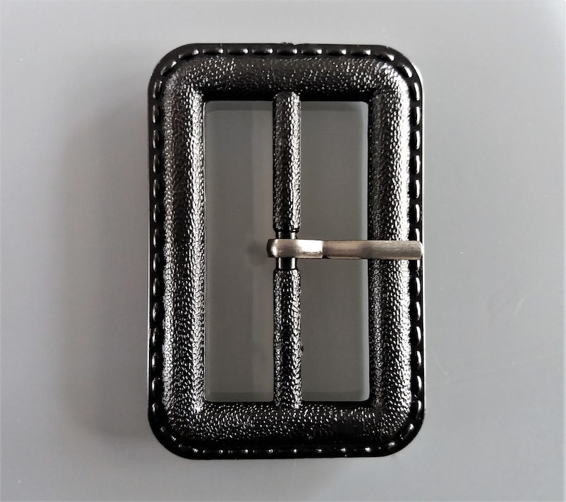 May include: Black plastic belt buckle with a silver metal slider.