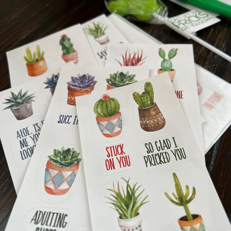 May include: A selection of white stickers with watercolour illustrations of cacti and succulents in pots. Some stickers have phrases such as "Stuck on You" and "So Glad I Pricked You".