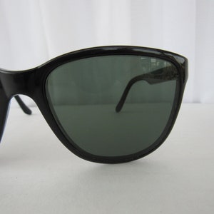 May include: Black cat-eye sunglasses with dark green lenses.