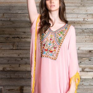 May include: A pink, long-sleeved kaftan with yellow fringe trim and colourful embroidery featuring flowers and birds.