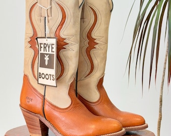 Può includere: Un paio di stivali da cowboy Frye in pelle beige e arancione. Gli stivali hanno la punta, il tacco impilato e cuciture decorative. Un'etichetta con il logo Frye pende da uno stivale.