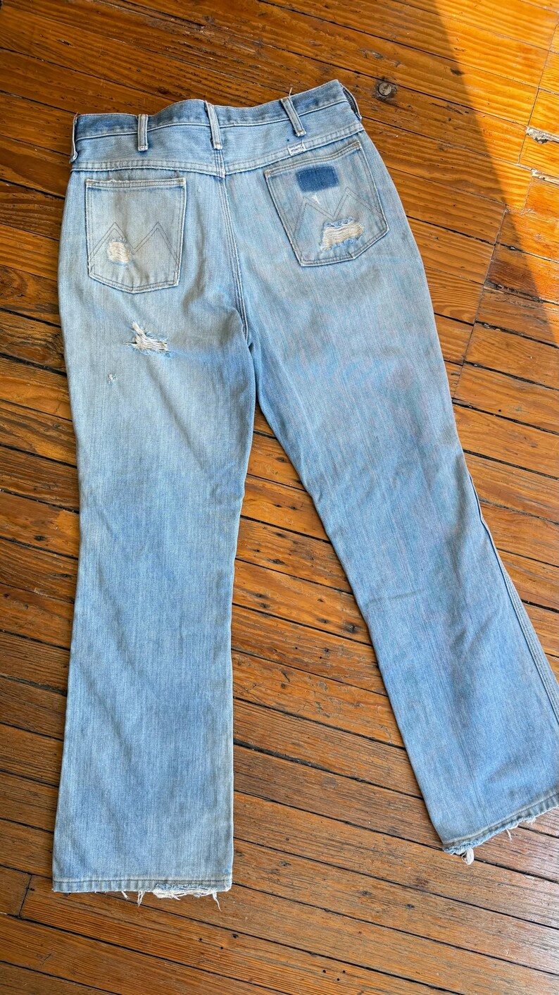 Op de afbeelding: Lichtblauwe jeans met een distressed design. De jeans hebben een klassiek ontwerp met vijf zakken, een hoge taille en een uitlopende pijp. De achterzakken hebben een uniek gestikt ontwerp. De jeans vertonen tekenen van slijtage, wat bijdraagt aan hun vintage uitstraling.