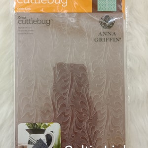 May include: A clear plastic package containing a Cricut Cuttlebug embossing folder. The folder is designed with a Celtic Link pattern and is labeled "Celtic Link". The package also features the Anna Griffin logo.