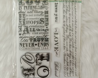 May include: Clear stamp set with the word "LOVE" in various fonts and sizes, along with related phrases like "I love you" and "Beloved." The set includes text from 1 Corinthians 13:4-8. The stamps are packaged in a clear plastic sleeve.