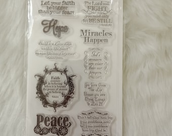 May include: A set of 13 clear stamps with inspirational quotes and phrases, including "Hope", "Miracles Happen", "Peace", and "Love". The stamps are on a white background with a light gray texture.