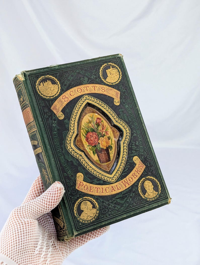 May include: A dark green hardcover book titled Scott's Poetical Works with gold embossed lettering and decorative borders. The cover features a central oval inlay depicting a colorful floral bouquet and four circular portraits of historical figures.