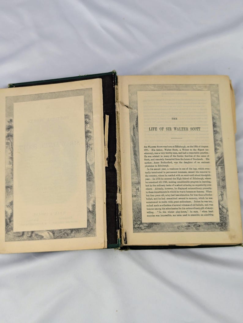 May include: An open antique book titled The Life of Sir Walter Scott with aged, cream-colored pages. The left page features a decorative border, while the right page contains printed text detailing the biography of Sir Walter Scott.