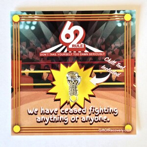 May include: A silver boxing glove charm with the text "62 RULE" and the phrase "Don't take yourself too damn seriously" on a red and yellow background. The text "Chill Tool Included" is also on the card.