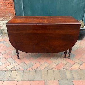 May include: A white ceramic mug with a black handle and the text "But First, Coffee" in a black, handwritten-style font. The mug is on a white surface.
