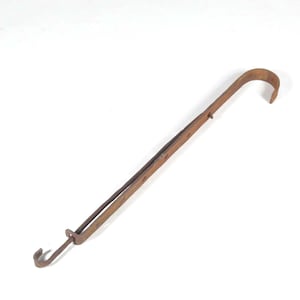 May include: A rusty metal hook with a long handle. The hook is bent at a 90-degree angle and has a small loop at the end of the handle.