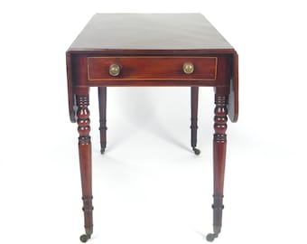 May include: A mahogany drop-leaf table with a single drawer and turned legs. The table has brass hardware and casters.