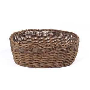 May include: A brown wicker basket with an oval shape. The basket is made of woven twigs and has a natural, rustic look.