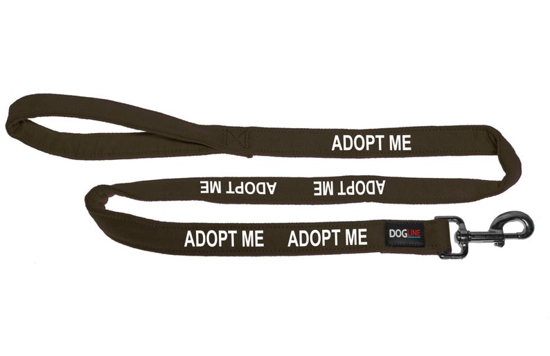 May include: A brown dog leash with a silver clip. The leash has the words "Adopt Me" printed on it multiple times.