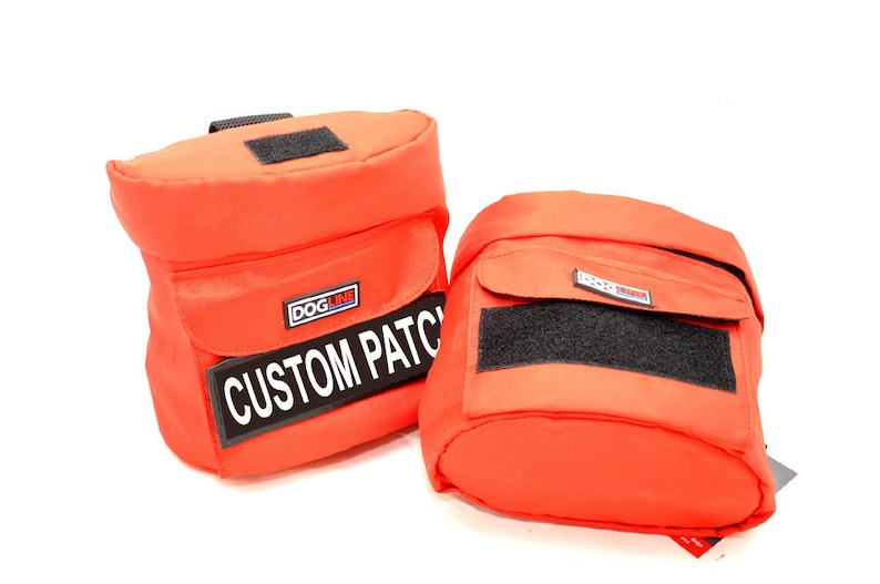 May include: Two vibrant orange pouches with black velcro patches and a rectangular flap. One pouch features a label that reads "CUSTOM PATCH". These pouches are likely designed for carrying items.