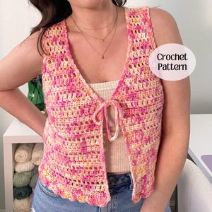May include: A sleeveless crochet vest featuring a variegated yarn pattern in shades of pink, peach, and yellow. The vest has a V-neckline, a front tie closure, and a scalloped hem. The text "Crochet Pattern" is visible in a white oval overlay.