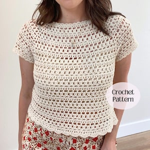 May include: A cream-colored short-sleeve top made with an open-work crochet pattern featuring a round neckline and a scalloped hem. A circular graphic overlay on the right side displays the text Crochet Pattern in black lettering.