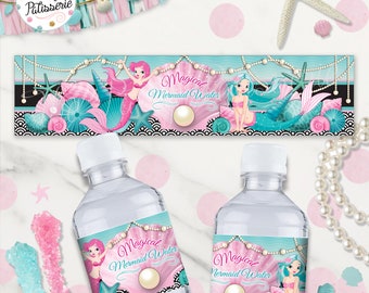 Peut inclure: Deux bouteilles d'eau en plastique transparent avec des étiquettes qui disent "Magical Mermaid Water". Les étiquettes représentent une sirène avec des queues rose et bleue, des coquillages et des perles.