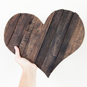 May include: A dark brown wooden heart-shaped sign made from reclaimed wood planks.