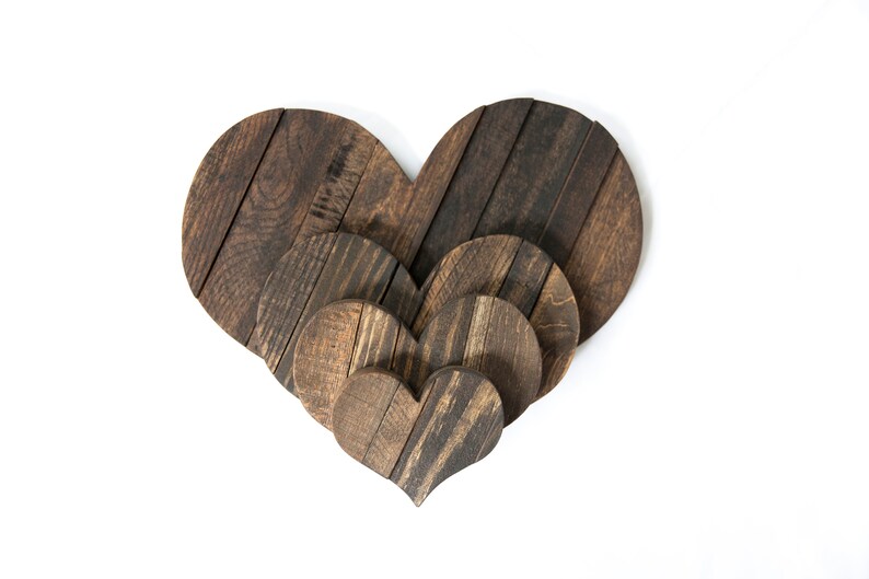 May include: Three wooden hearts of varying sizes, nested together. The hearts are made of dark brown wood with a rustic finish.