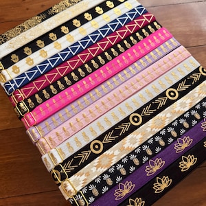 May include: A white ceramic mug with a black handle and the text "But First, Coffee" in a bold, black font. The mug is set against a blurred background, suggesting a cozy setting.