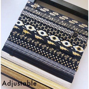 May include: A collection of black and gold elastic book bands with various patterns, including geometric designs, musical notes, and flamingo silhouettes. The text "Adjustable Book Bands" and "Great for bookmarks, planners, notebooks etc." is displayed below the bands.