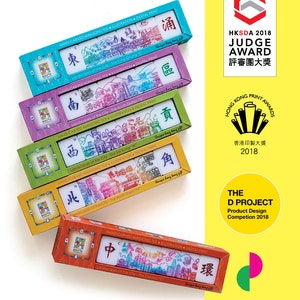 Peut inclure: Plusieurs bo&icirc;tes color&eacute;es de tuiles de Mahjong sculpt&eacute;es &agrave; la main. Chaque bo&icirc;te pr&eacute;sente une couleur diff&eacute;rente et contient des tuiles avec des illustrations de villes et des caract&egrave;res chinois. Les bo&icirc;tes sont &eacute;tiquet&eacute;es avec le texte "HAND-CARVED MAHJONG TILE ILLUSTRATION DIGITAL PRINT."