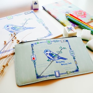 May include: A light blue Mahjong Making Tools pouch with a blue bird illustration, surrounded by a blue frame with text. A matching notebook and pencils are also visible, along with Mahjong tiles.