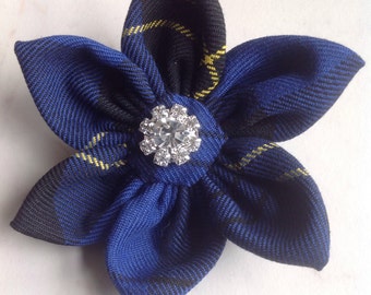May include: A blue and black plaid fabric flower with a clear rhinestone in the center.