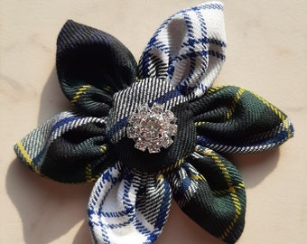 May include: A green, blue, and white plaid fabric flower with a silver rhinestone button in the center.