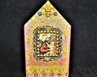 May include: A small pink wooden house with a gold filigree design and a picture of the Madonna and child inside. The house has a gold fleur-de-lis on the top.