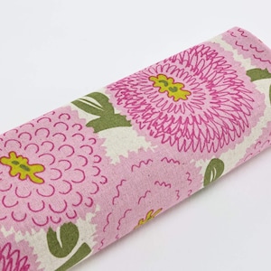 Peut inclure: Tissu roulé avec un motif floral. De grandes fleurs roses avec des centres jaunes et des feuilles vertes se détachent sur un fond crème. Le tissu est adapté aux projets de couture ou d'artisanat, avec des mesures en centimètres.