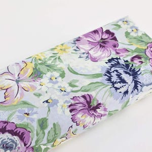 Peut inclure: Un tissu bleu clair avec un motif floral composé de fleurs violettes, jaunes et vertes. Le tissu est doux et délicat au toucher et est parfait pour les projets de bricolage.