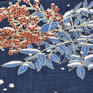 May include: Close-up of a navy blue fabric with a floral design. The design features red berries, blue leaves, and white accents, possibly depicting a winter scene. The leaves have gold outlines.